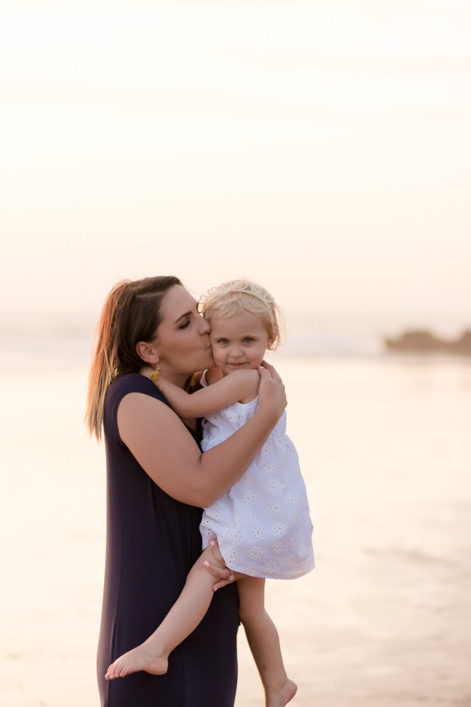 Mom kissing daughter at sunset during a Sedgefield beach photoshoot