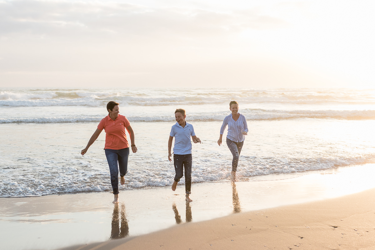 two mothers and their son playing on a beach at sunset in Sedgefield garden route during a photoshoot by moi du toi photography