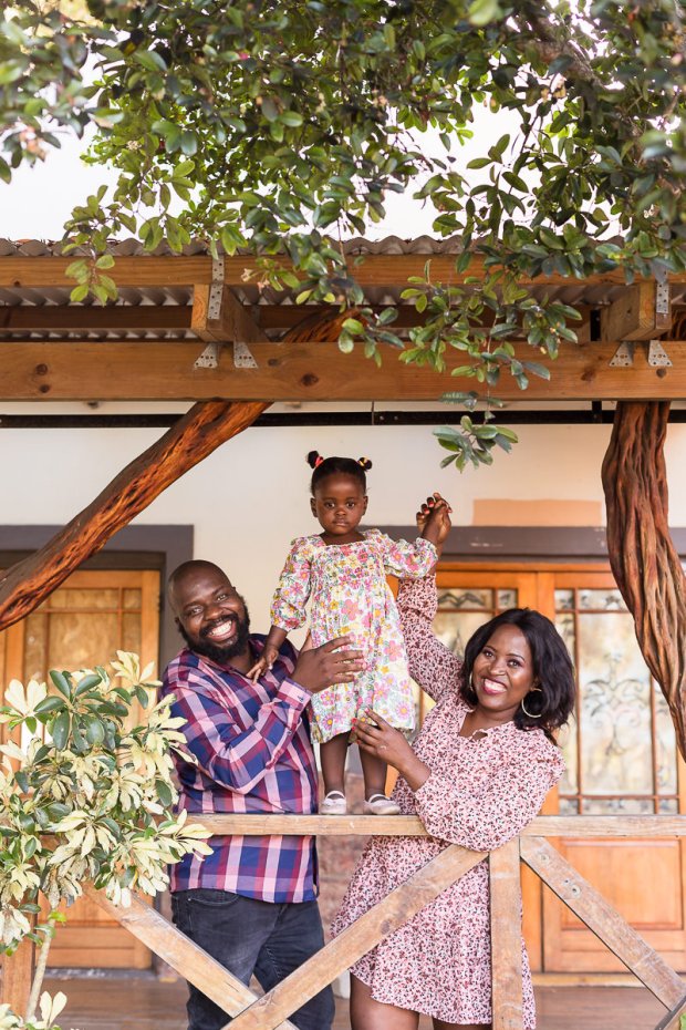 toddler standing on railing held by parents