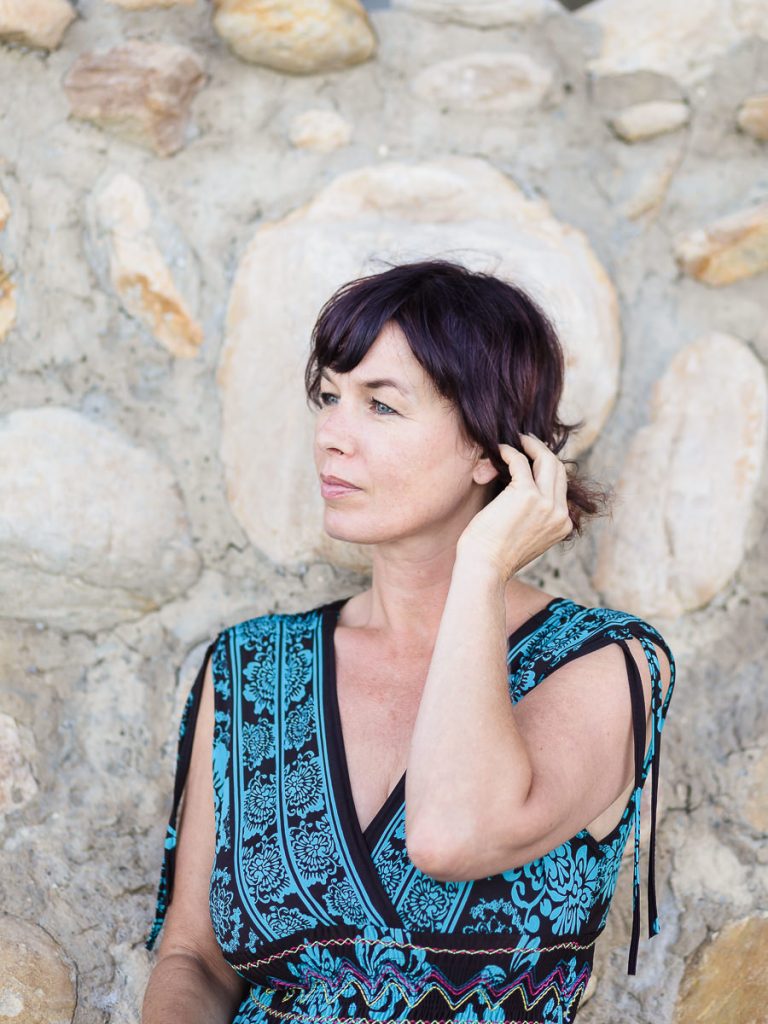 woman leaning against stone wall at Leisure Island Beach during personal branding session photographed by moira du toit of moi du toi photography