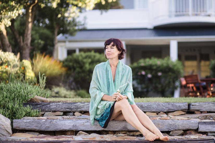 woman sitting on wooden steps and draped with green shawl at Leisure Island Beach during personal branding session photographed by moira du toit of moi du toi photography