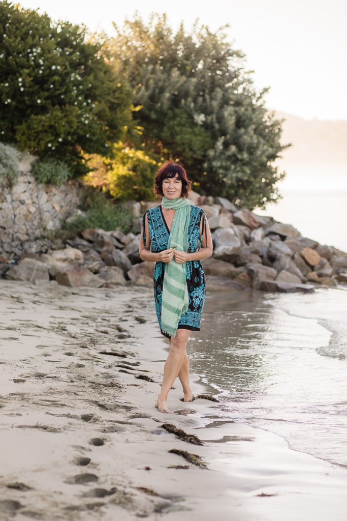 woman walking draped with green shawl at Leisure Island Beach during personal branding session photographed by moira du toit of moi du toi photography