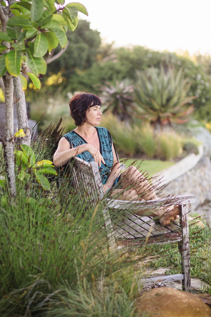 woman sitting on wooden beach gazing outwards at Leisure Island Beach during personal branding session photographed by moira du toit of moi du toi photography
