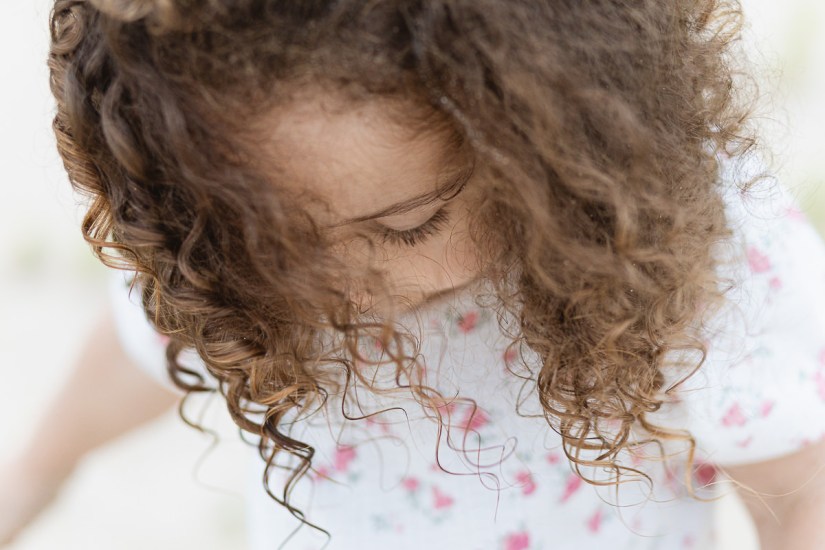 young girl with curly hair during light and airy family session at Cola Beach sedgefield photographer moi du toi