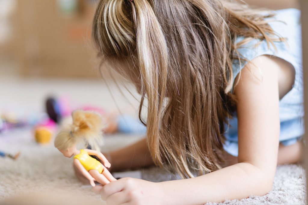 Girl playing with doll during light and airy slice of life family session at Cola Beach by sedgefield photographer moi du toi