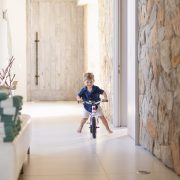 little boy riding his bike down hallway during light and airy slice of life family session at Cola Beach by sedgefield photographer moi du toi
