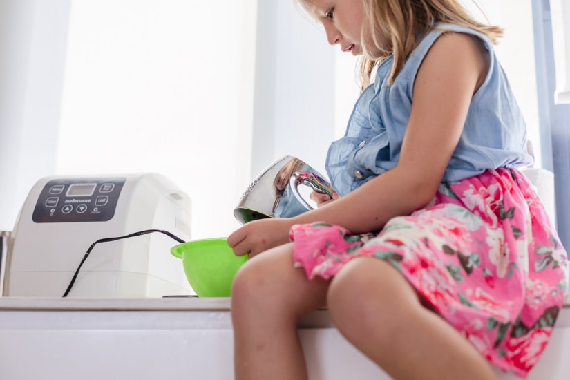 girl mixing cookie dough in bowl during light and airy slice of life family session at Cola Beach by sedgefield photographer moi du toi