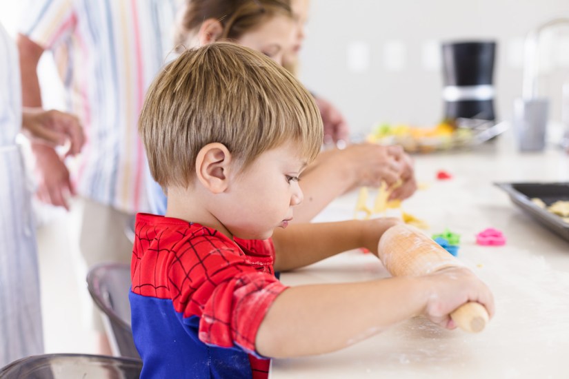 little boy rolling dough with rolling pin during light and airy slice of life family session at Cola Beach by sedgefield photographer moi du toi