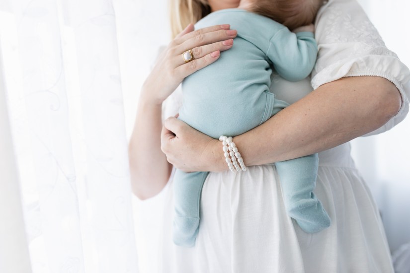 mother winding baby during lifestyle newborn photo session with photographer moi du toi photography