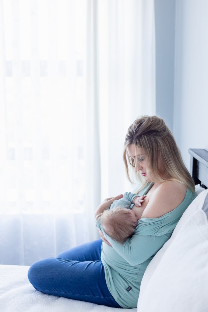 mother holding and breast feeding newborn during photo session with photographer moi du toi photography