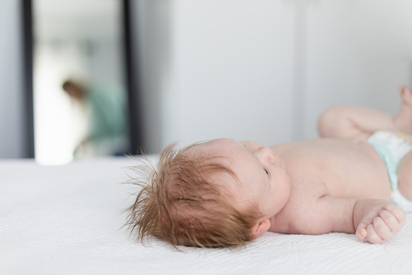 mother changing baby during lifestyle newborn photo session with photographer moi du toi photography