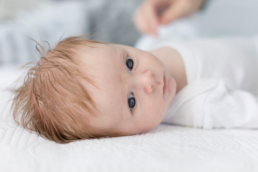 newborn lying on white blanket during lifestyle newborn photo session with photographer moi du toi photography
