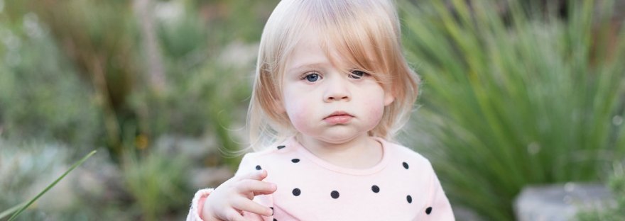 Full length shot of Toddler dressed in pink walking down path towards the camera, blurred out greenery at Woodlands self catering accommodation in the background during a lifestyle family photo shoot by a Sedgefield photographer moi du toi photography