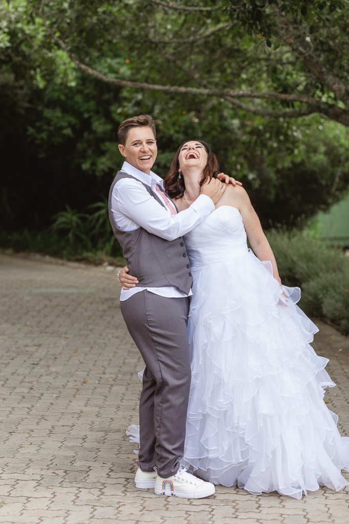 Gay wedding couple laughing and having fun together in a garden
